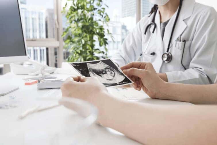 医師と胎児の超音波写真を見る女性の手