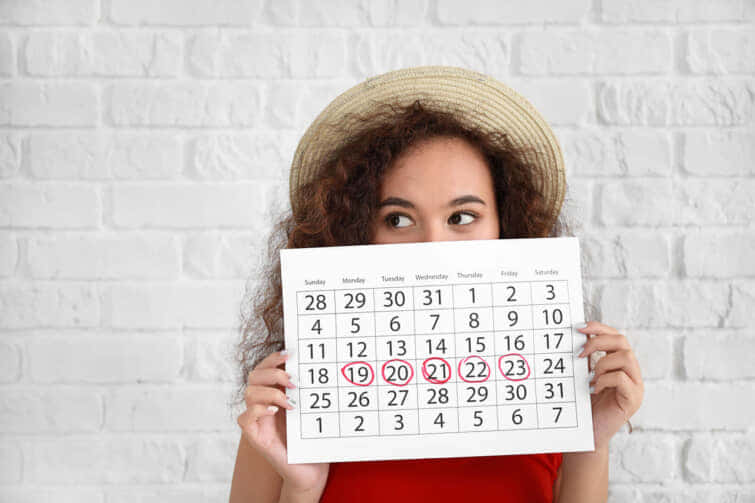 白い背景に著しい月経日を持つカレンダーを持つアフリカ系アメリカ人の女性