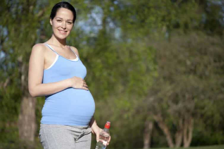 水瓶を持つ屋外の妊婦