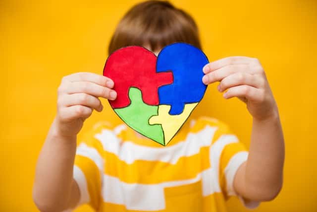 パズルの心を持つ少年の手、子どもの精神衛生のコンセプト、世界の自閉症意識の日、十代の自閉症スペクトル障害の認識のコンセプト