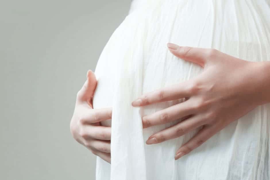 お腹を抑えて赤ちゃんを心配をしている妊娠中期の女性