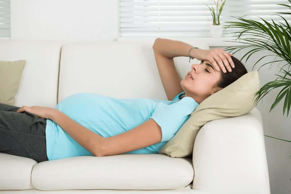 身体がだるくてソファで横になる妊娠中期の女性