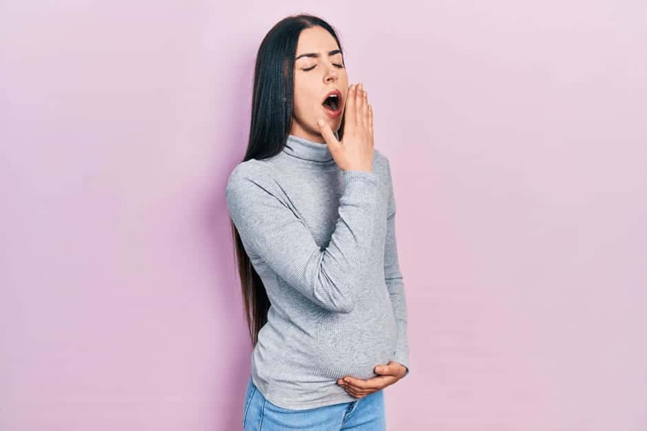 眠くてあくびをする妊娠中期の女性