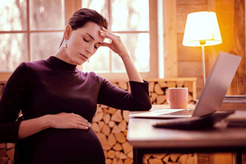 動悸がつらくて頭をおさえている妊娠中期の女性