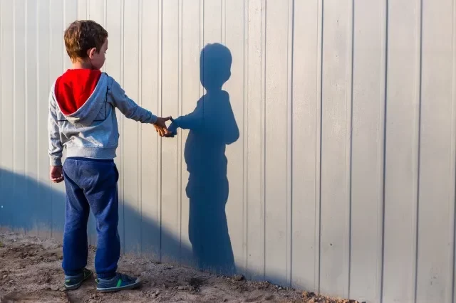 男の子と影。外で影で遊んでいる孤独な小さな子ども。自閉症と孤独のコンセプト