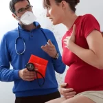 医師から動悸について説明を受けている妊娠中期の女性