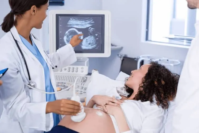 妊娠中の女性の腹部エコーをする医師