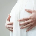 お腹を抑えて赤ちゃんを心配をしている妊娠中期の女性