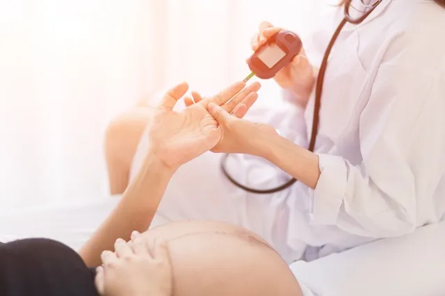女性の産科医が病院で妊婦の血糖値を測定します。 妊娠糖尿病の概念。