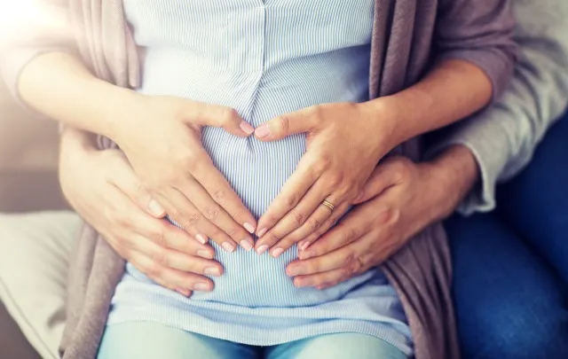 妊娠、愛、家族、人々のコンセプト – 腹に手で心臓のジェスチャーをする妊婦の接写