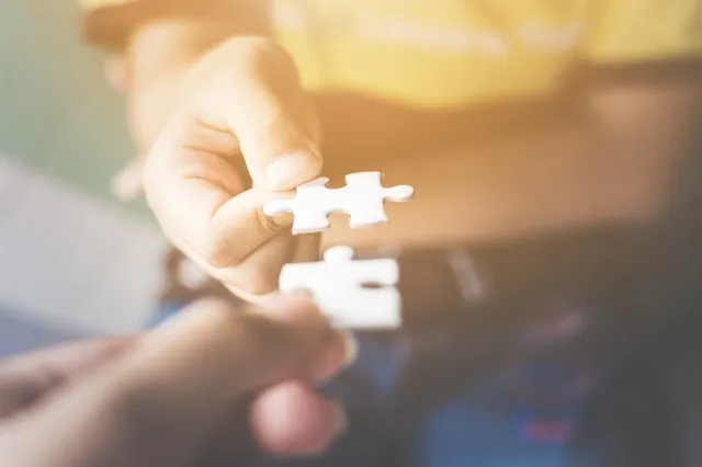 一緒に接続するジグソー パズルを保持している 2 人の手。 ビジネス戦略におけるパートナーシップとチームワークの概念