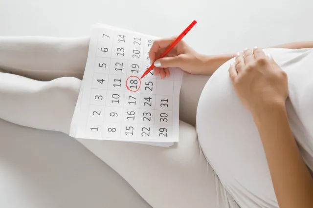 カレンダーで出産日をマークする若い妊婦。 コンセプトを期待している赤ちゃん。 将来の計画。