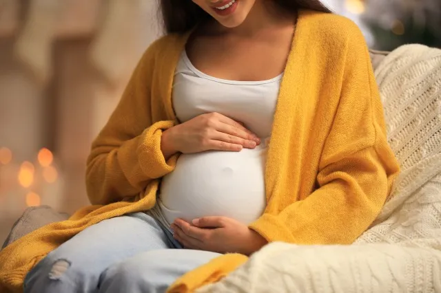 クリスマス、クローズ アップのために飾られた部屋で肘掛け椅子で幸せな妊娠中の女性。 妊娠中の赤ちゃん
