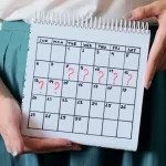 マークされた逃した期間のカレンダーを保持している女性。 望まない妊娠、女性の健康、月経の遅れ。