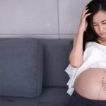 妊娠中の女性は、子宮内の子供を心配しながら座っています