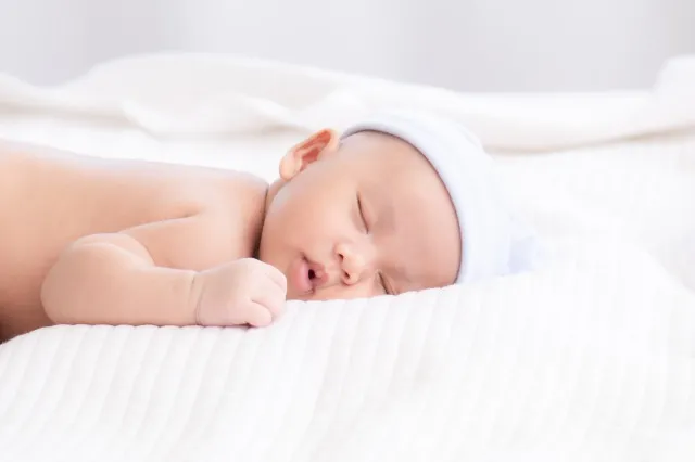 愛らしいアジアの生まれたばかりの赤ちゃん深く眠っている笑顔イースター コスチューム帽子、ベッドの上の白い毛布の上に小さな幼児男の子の柔らかい肌の健康的な睡眠の夢美しい太陽の光、生まれたばかりの赤ちゃんのヘルスケアの概念