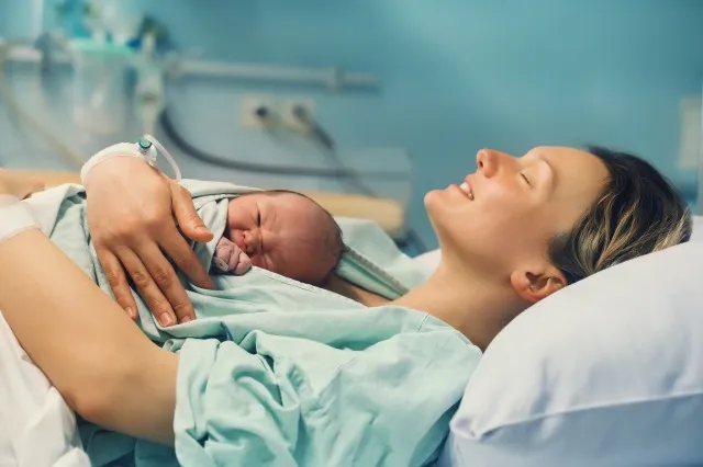 母と新生児。 産院で出産。 出産後、生まれたばかりの赤ちゃんを抱きしめる若いお母さん。 出産する女性