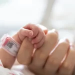 生まれたばかりの赤ちゃんの手は、お母さんの人差し指を握ります。 コンセプト: 入院中の未熟児または早産児。 母親と赤ちゃんの関係。