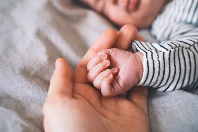 赤ちゃんの手が親の手に。 家族の幸せのコンセプト。 生後数日で眠っている新生児。 赤ちゃんの手を握る母親