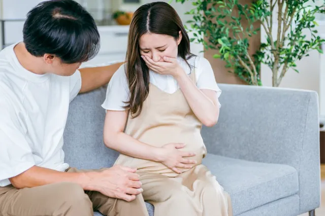 出産直前の妊婦と心配する男性（吐き気）