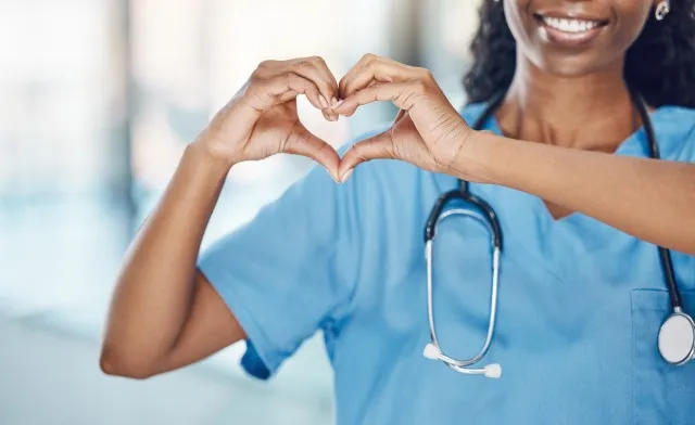 愛とキャリアへのケアを示す表情で病院のハートハンドと黒人女性看護師。 仕事で幸せな笑顔と自己愛のサインと制服を着た専門の医療施設労働者