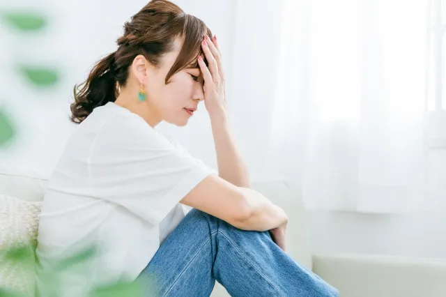部屋で頭痛・ホルモンバランスの乱れやストレスで悩む日本人女性