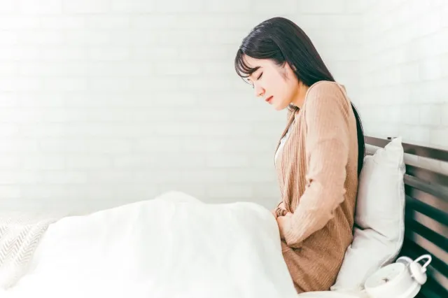 ベッドルームで腹痛・生理痛に悩む日本人女性
