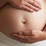 黒の背景に5ヶ月の妊娠中の女性の肖像画をクローズアップ