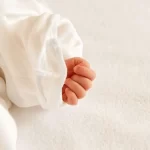 白いベビー服を着て横になっている赤ちゃん