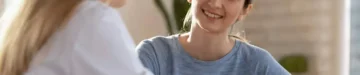 生まれてくる子どもに疾患がないか不安で遺伝カウンセリングを受けに来た女性と優しく出迎える女性医師
