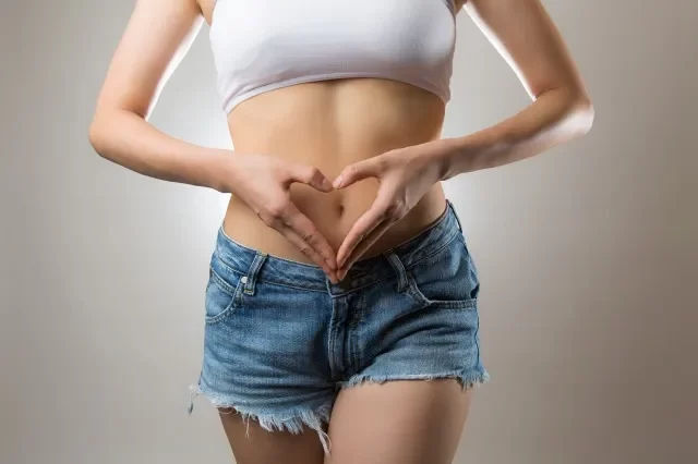 お腹にハートマークを作る女性
