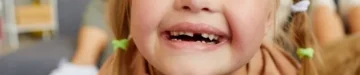 自宅のソファに横たわっている間カメラを見て幸せそうに笑っているダウン症のブロンドの女の子の肖像画を間近します。