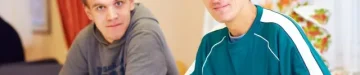 リハビリテーション センターの机に座っている障害を持つ陽気な成人男性
