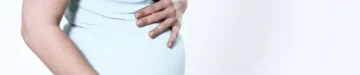 膨満感のある女の子が立っていて、痛みを感じています