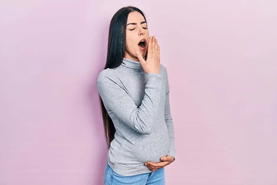 眠くてあくびをする妊娠中期の女性