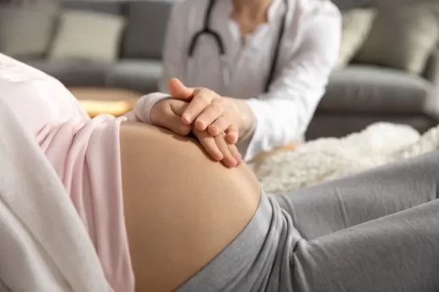 産前ケア。 女医家族セラピスト産婦人科サポート コンフォートは、若い妊婦患者を助けます。 健康診断でお腹を愛撫する妊婦の手に触れる医療従事者。 ビューをクローズ アップ