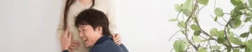 妊娠中の妻のお腹に耳を当てる男性
