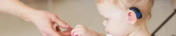 女の赤ちゃんの耳に補聴器。 家で補聴器を装着している幼児。 障害児、障害、難聴のコンセプト。