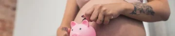 妊娠中の女性が貯金箱にお金を入れて、接写。 高品質の写真