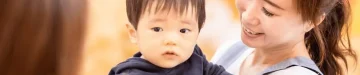 保育園で保育師さんに抱っこされている赤ちゃん