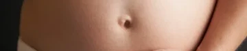 黒の背景に5ヶ月の妊娠中の女性の肖像画をクローズアップ