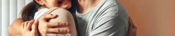 シンプルで清潔な医療オフィスを背景に、カジュアルな服装のアジア人夫婦が喜びの涙を流しながら抱き合うシーン